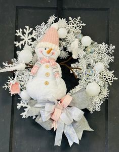 a snowman wreath on the front door is decorated with white and pink ornaments,