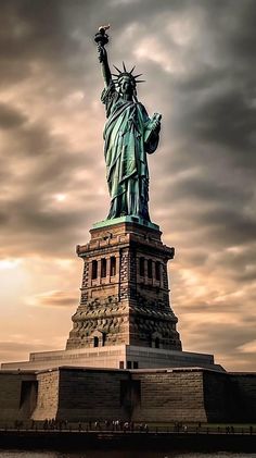 the statue of liberty is shown against a cloudy sky