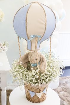 a teddy bear in a hot air balloon filled with baby's breath and flowers