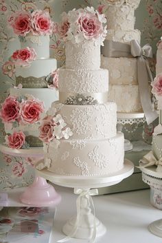 there are many different types of wedding cakes on the table with pink flowers and ribbons around them