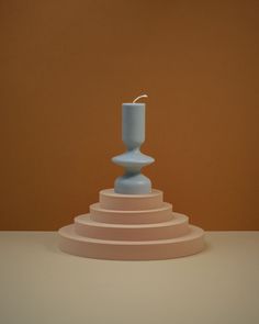 a blue candle holder sitting on top of a set of three white steps in front of an orange wall