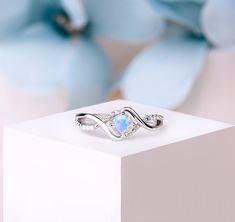 a white gold ring with an opal center surrounded by diamonds and blue flower petals