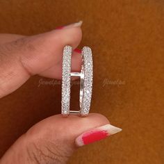 a woman's hand holding two wedding rings on her finger with red nail polish