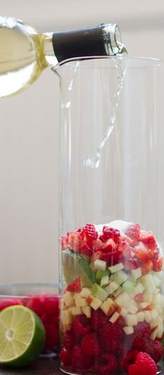 someone is pouring dressing into a jar with strawberries and raspberries in it