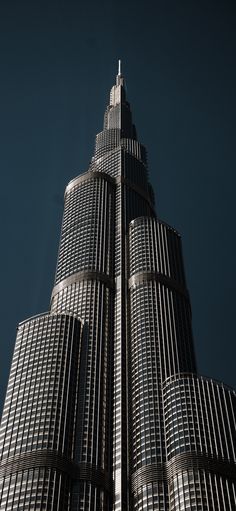 the top of a tall building with lots of windows on it's sides, against a dark blue sky