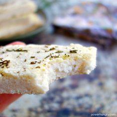 a hand holding a piece of food with some herbs on it's top and the other side