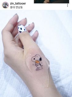 a person with a small tattoo on their left hand holding a tiny white object in the other hand