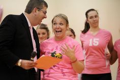 a man and woman in pink shirts are talking to each other while others look on