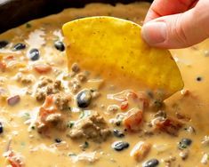 a hand dipping a tortilla chip into a bowl of quesadilla soup