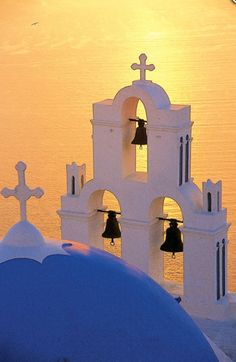 the bell tower has two bells on each side and is next to an ocean with cross silhouettes