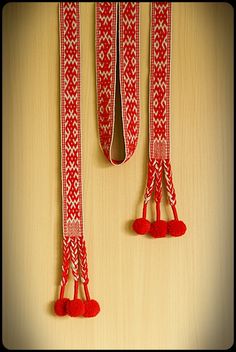 red and white ribbon with pom - poms hanging from it's sides