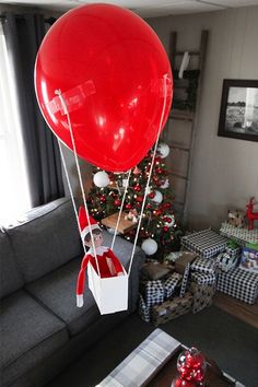 a living room decorated for christmas with presents and a large red balloon in the air