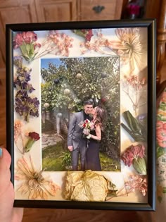 a man and woman are kissing in front of a picture frame with flowers on it