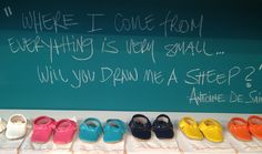 there are many pairs of shoes lined up in front of a chalkboard that says, where i come from everything is very small will you draw me a step?