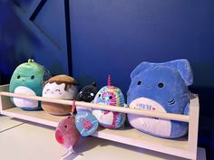 stuffed animals are lined up on a shelf in front of a blue wall and wooden frame