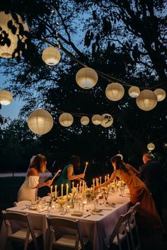 a group of people sitting around a table covered in paper lanterns