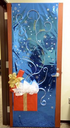 a door decorated with blue paper and gold ribbon, presents tied to the side in front of it