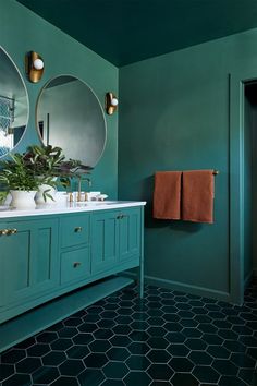 a bathroom with green walls and two round mirrors