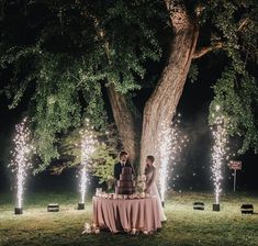 a bride and groom are standing under a tree with their wedding cake on the table