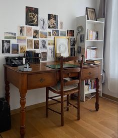 a wooden desk topped with a glass top computer monitor next to a book shelf filled with books