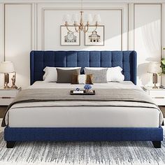 a bed with blue headboard and foot board in a white walled room, with two lamps on either side of the bed