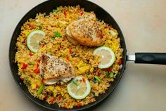 a skillet filled with rice, chicken and vegetables