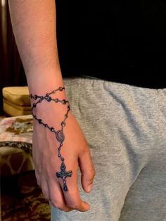 a man with a rosary tattoo on his wrist and hand is holding the cross in front of him