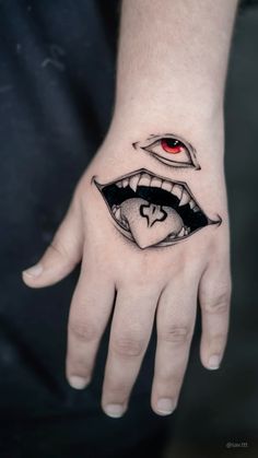 a woman's hand with a tattoo on it that has an evil face and red eyes