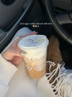 a woman is holding a cup of coffee in her hand while sitting in the driver's seat