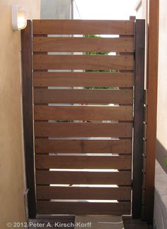 an open wooden gate on the side of a building