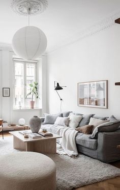 a living room filled with furniture and a white rug on top of a hard wood floor