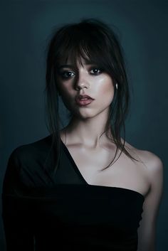 a woman in black dress posing for the camera with her eyes closed and dark background