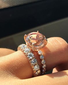 a woman's hand with two rings on top of her finger and an orange diamond in the middle