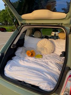 an open trunk of a car with a bed and pillows in the back seat area