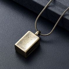 a square pendant is sitting on a black surface