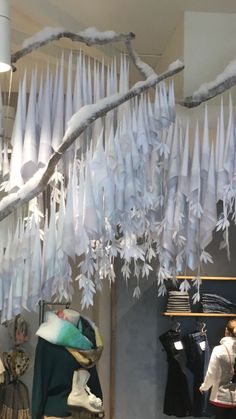 an assortment of clothing and hats on display in a store window with icicles hanging from the ceiling