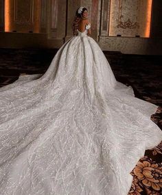 a woman in a white wedding dress standing on the floor with her back turned to the camera