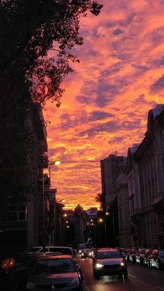 cars are parked on the street as the sun sets