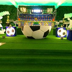 a large soccer ball sitting on top of a green field next to other trophies and decorations