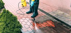 a person using a pressure washer to clean the sidewalk