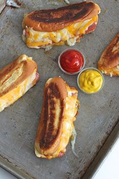 three hot dogs on a tray with mustard and ketchup next to each other