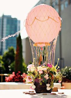 a table topped with a vase filled with flowers and a hot air balloon in the background