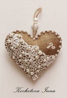 a heart shaped ornament with pearls and lace in the shape of a heart