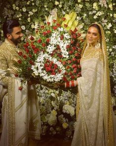 the bride and groom are standing in front of a flower arrangement