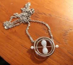 a silver necklace with an image of a person in a circle on it sitting on top of a wooden table