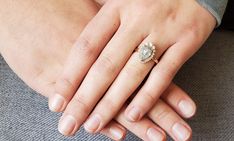 a close up of a person's hand with a diamond ring on their finger