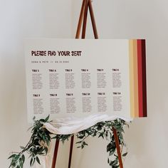 a seating chart is displayed on an easel with greenery and flowers around it