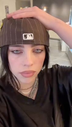 a woman with black hair wearing a baseball cap