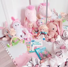 there are many stuffed animals and books on the floor next to each other in front of a mirror