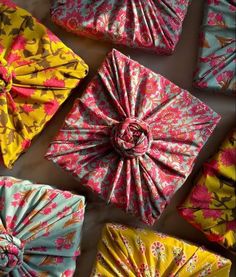 many different types of wrapped presents on a white tablecloth with pink, yellow and blue designs